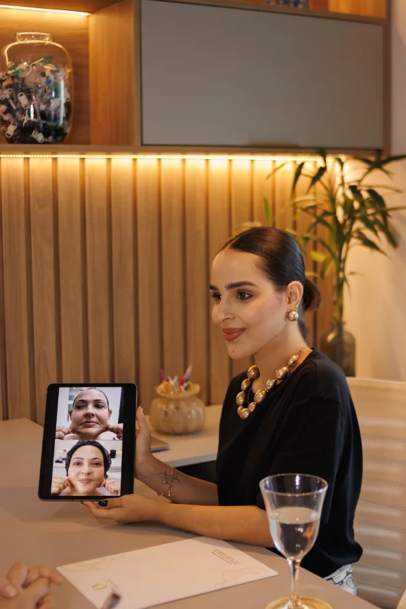 Dra. Duda Carreira em consulta, mostrando no tablet a análise do rosto da paciente